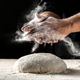 2 hands and raw dough covered in flour for baking